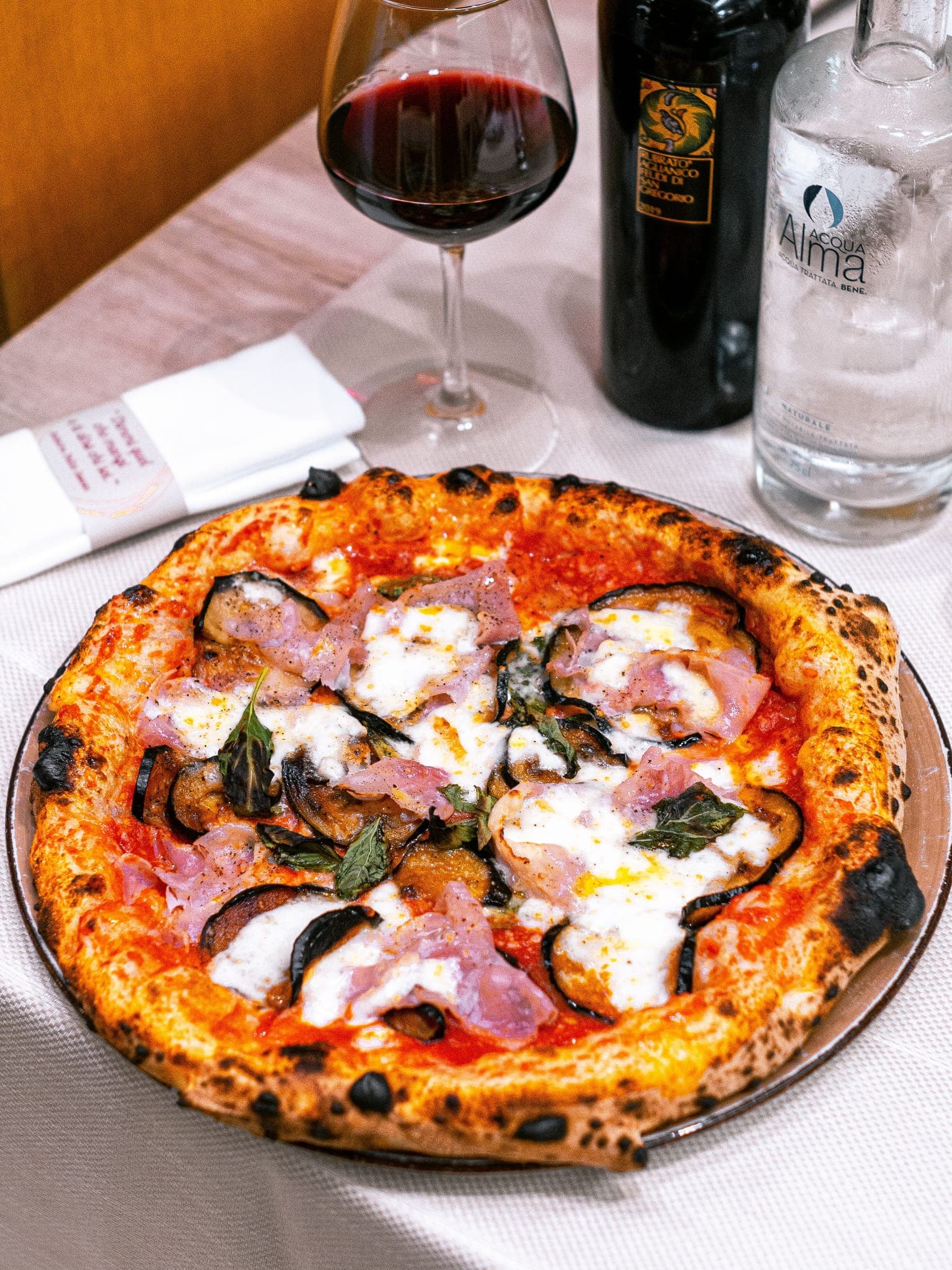 Pizza mięsna podana z kieliszkiem czerwonego wina